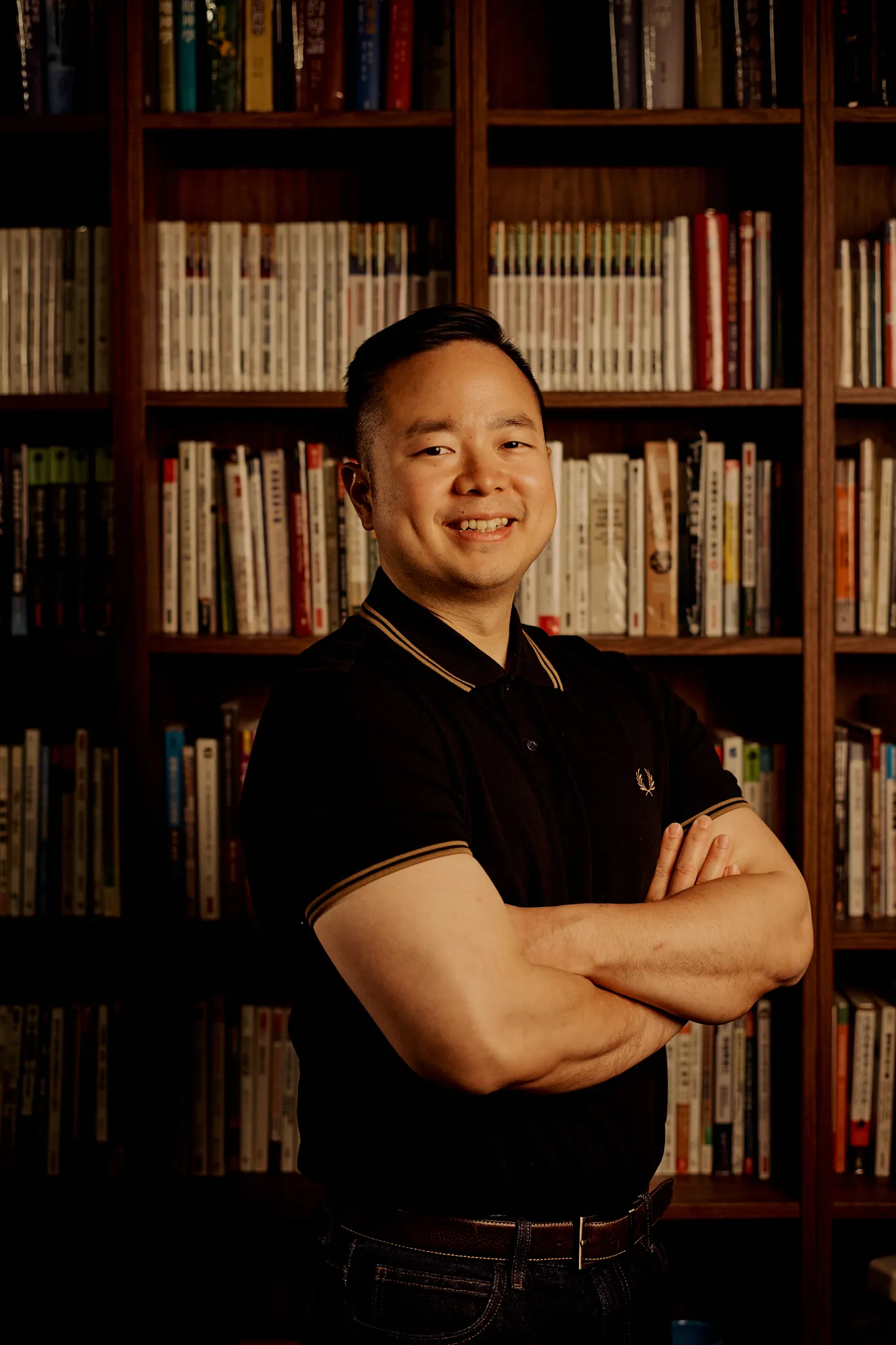 Andrew Yang standing in front of his book wall